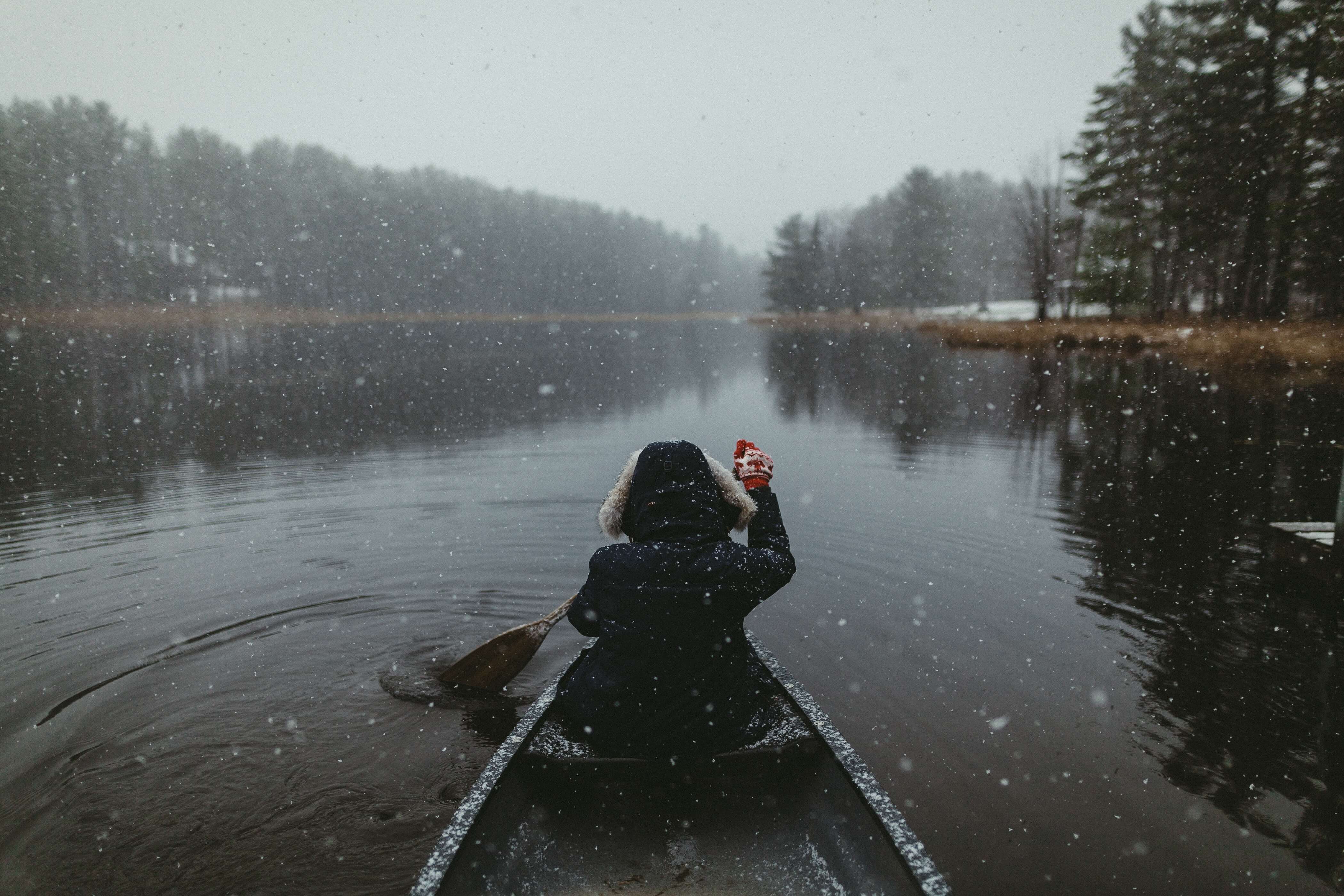 A person canoeing. It's snowing